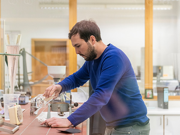 Mann im Labor, gießt Flüssigkeit in ein Messgerät