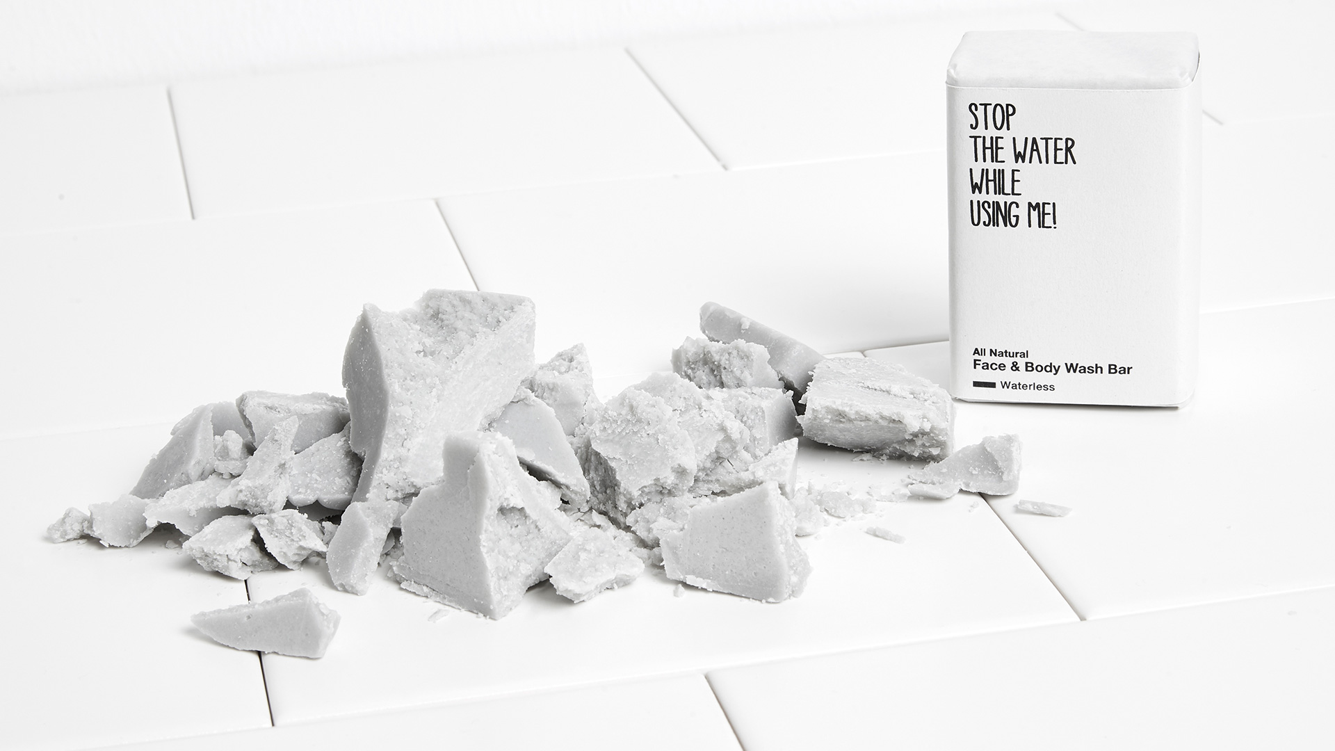 Zerkleinertes Face&Body Seife neben einer in Papier verpackten Stop the water while using me Seife