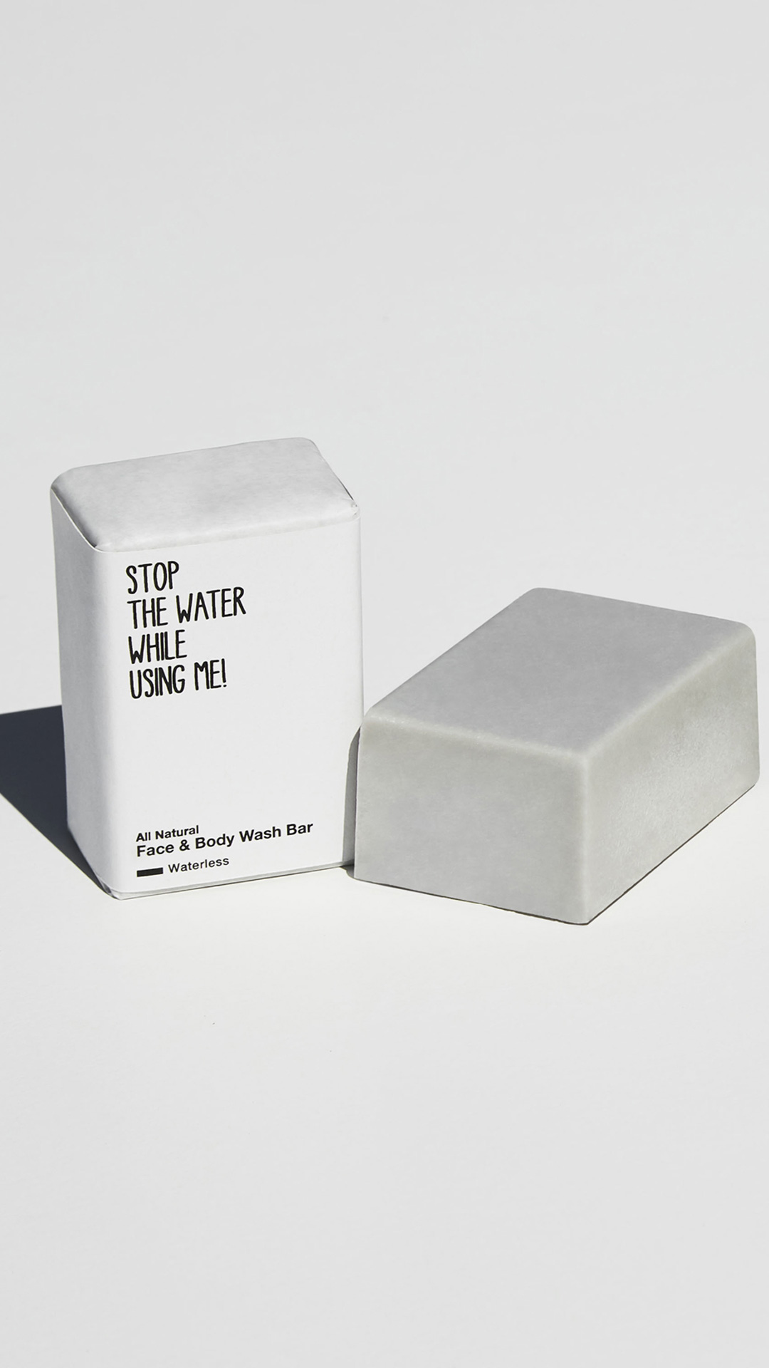 Feste Seife für Körper und Gesicht von Stop the water while using me verpackt mit nachhaltigem Papier und daneben eine unverpackte Seife