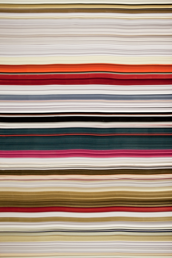 Farbiges Papier von braun bis blau, pink aufeinander gestapelt. Frontal fotografiert